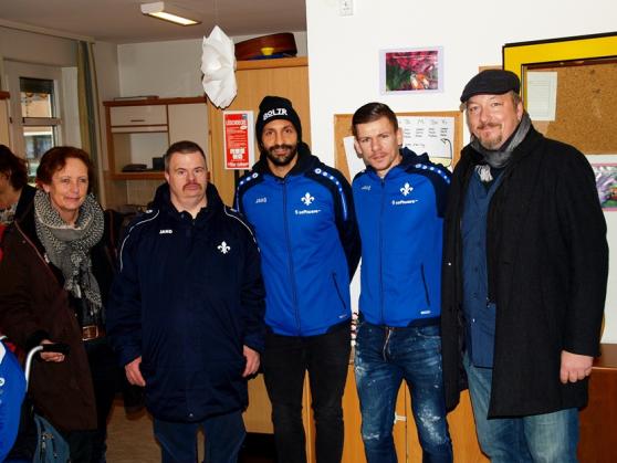 Stadträtin Akdeniz, die Lilienspieler Sulu und Bezjak und der Leiter der Darmstädter Werkstätten und Wohneinrichtungen Wolfram Cuntz bei der Übergabe der Weihnachtspäckchen an die Bewohnerinnen und Bewohner der Kurt-Jahn-Anlage © Wissenschaftsstadt Darmstadt 